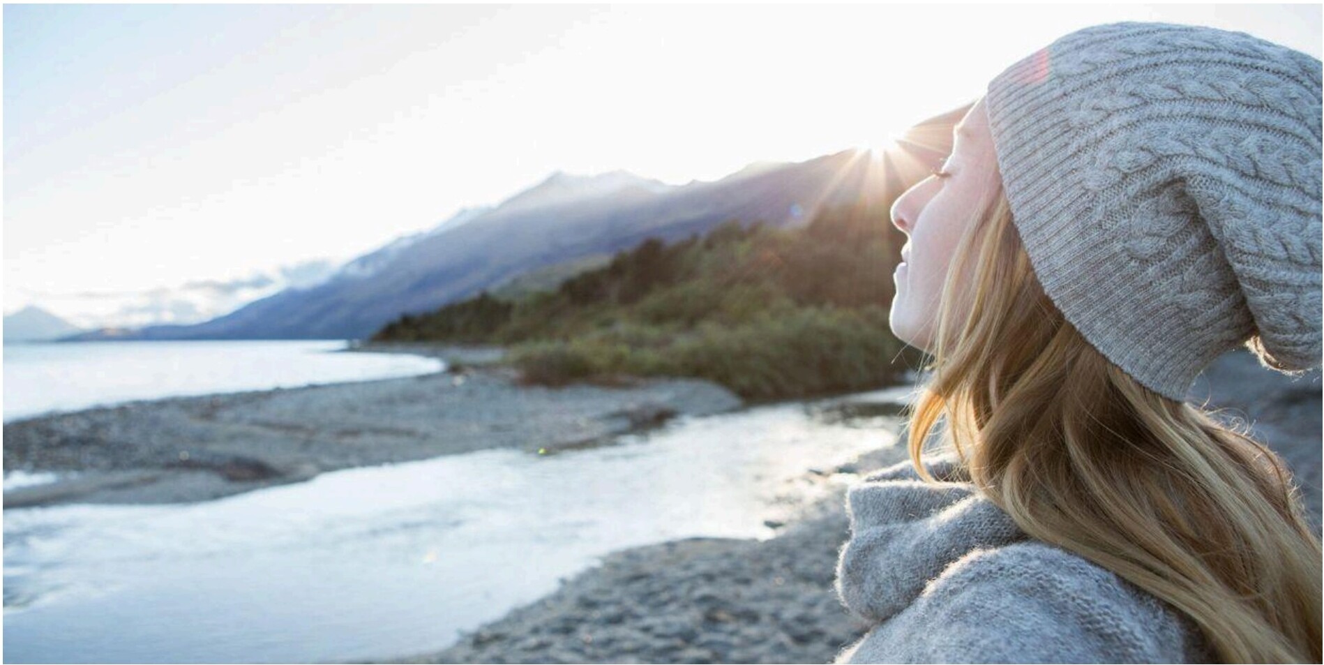Woman in knit hat looking out over mountains and water