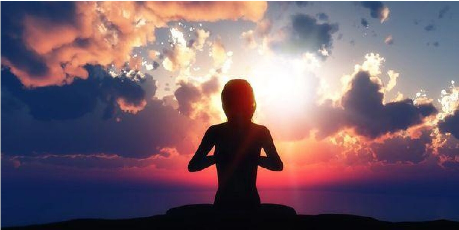 Silhouette meditating against a vibrant sunset sky